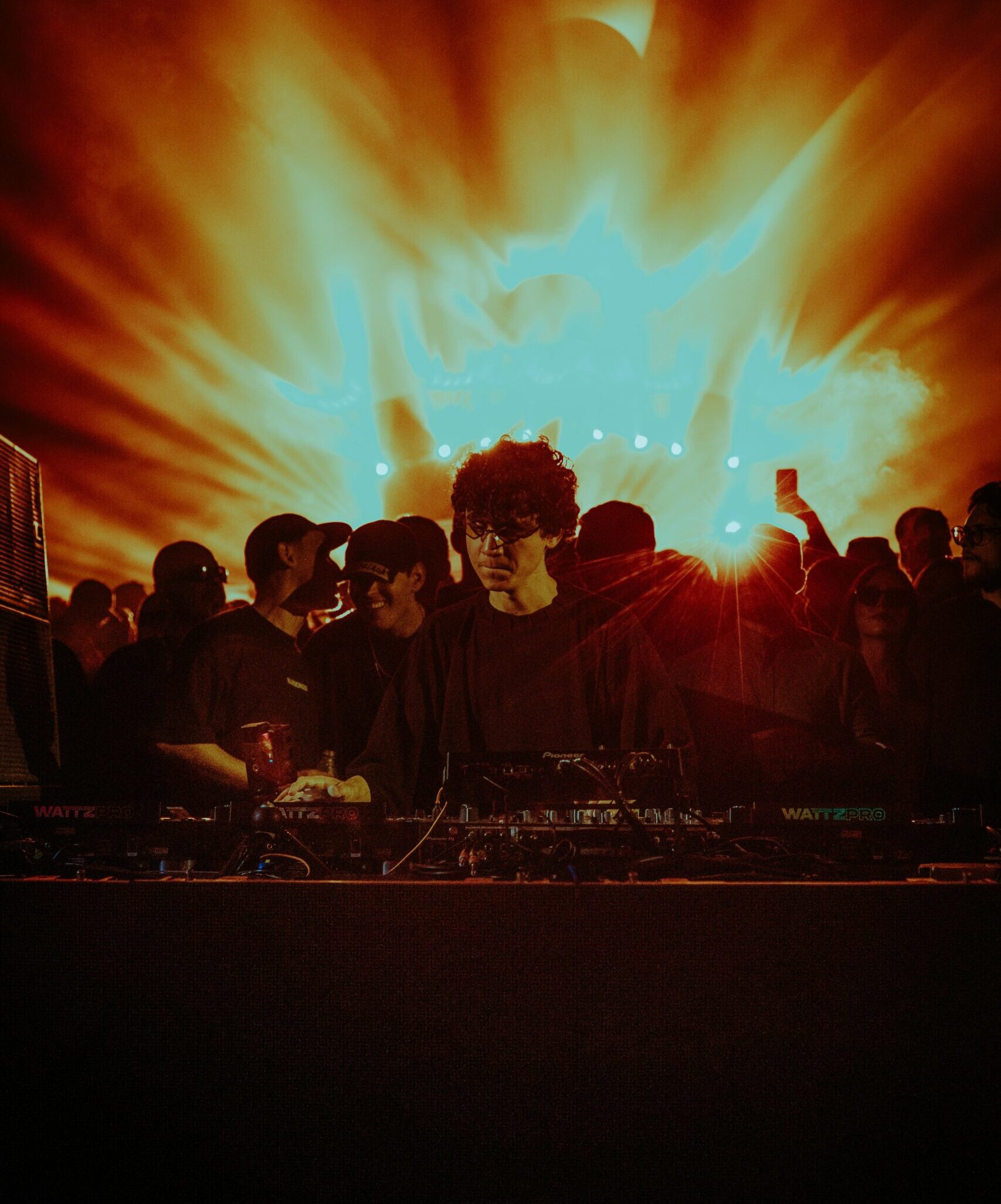 DJ performing in front of a lively crowd with stunning light effects.